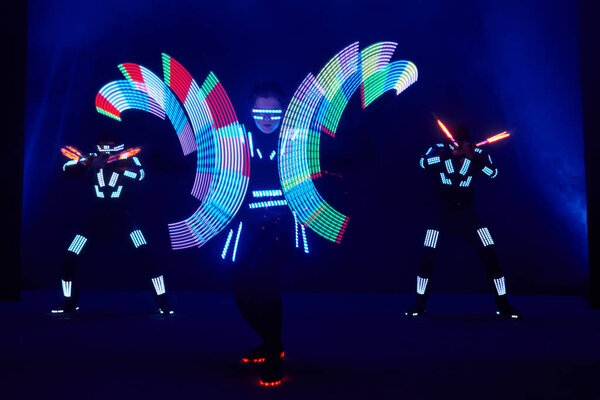 Laser show performance, dancers in led suits with LED lamp, very beautiful night club performance, party.