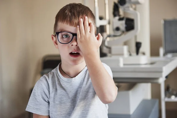 彼が何を見てるか教えて小さな男の子は彼の目を覆い 診療所で目を見て — ストック写真