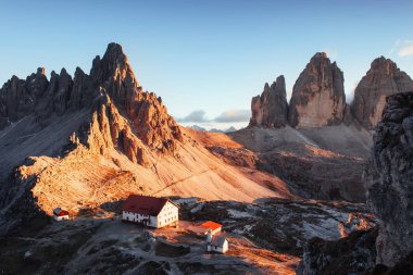 İki binanın ve insanların önünde. Gün batımında Paternkofel 'in büyük dolomite dağının fotoğrafı..