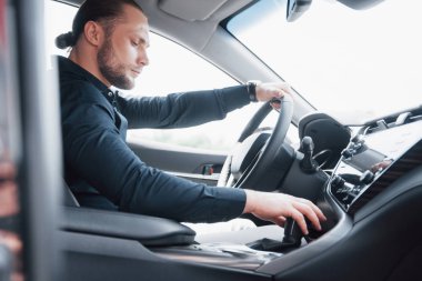 Kendine güvenen genç işadamı yeni arabasının direksiyonunda oturuyor..