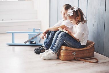 Büyük seyahate hazırız. Küçük mutlu kız ve çocuk büyük bir evrak çantası taşıyan ilginç bir kitap okuyor. Özgürlük ve hayal gücü kavramı.