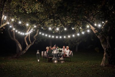 Başarıyı kutlayalım. Akşam vakti. Arkadaşlar muhteşem açık havada yemek yer..