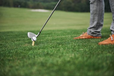 Yeşil bölge golf sahası, beyaz top ve metal sopa. Oyuncu sadece bacakları görebilir..