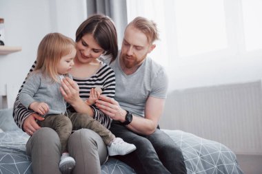 mutlu aile anne, baba ve çocuk kızı yatakta güler.