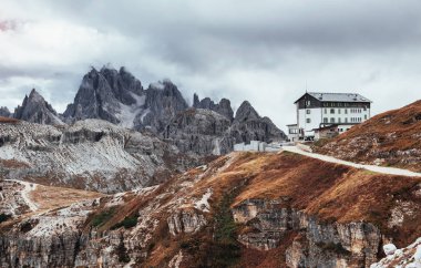 Tepelerde. Dağların tepesinde, bulutlu ve sisli uçurumların yanında duran bina..