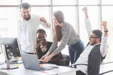 Kazanmış gibi görünüyor. Takım çalışanları gülümsüyor ve el kaldırıyor..