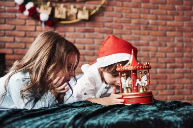 İlgi çekici çocuk gözleri. Çocuklar yeni yılda oyuncak atlıkarıncayla oynuyorlar. Bir kız kafasında Noel Baba şapkasıyla.