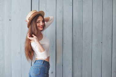 Muhteşem bir gülümseme. Şapkalı kız kameraya yan döndü. Ahşap arka planda duruyor..