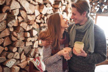 Genç çift kışın açık havada romantik bir kulübede kahvaltı yapıyor. Kış tatili ve tatil. Mutlu erkek ve kadınların Noel çifti sıcak şarap içer. Birbirine aşık çift.
