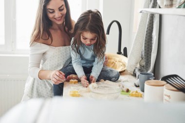 Masaya oturdum. Mutlu kız ve anne birlikte fırın ürünleri hazırlıyorlar. Mutfakta küçük bir yardımcı..