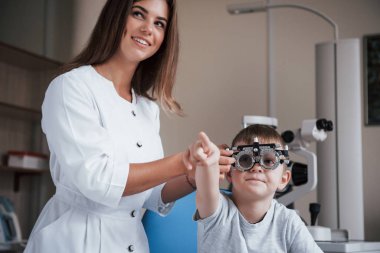 Çocuk işaret parmağıyla bir şey gösteriyor. Çocuk doktorun dolabında oturuyor ve görme yetisini test ediyor..