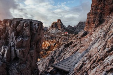 Tepelerin kıyısındaki aşırı turist yolu. Dolomit dağlarında dikilen ahşap köprüyle..