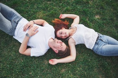Parktaki çimlerin üzerinde yatan romantik bir çift genç. Üst görünüm.