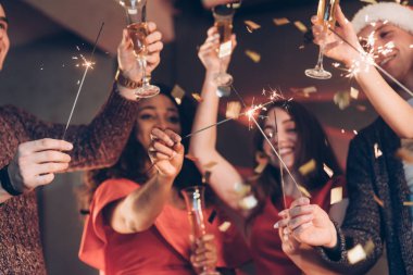 Bir dilek tut. Çok ırklı arkadaşlar yeni yılı kutluyor. Bengal ışıkları ve bardaklarla içki içiyorlar..