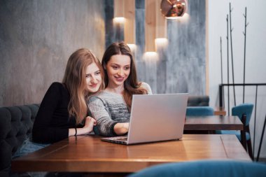 İnternette sörf yapan iki kız, bir dizüstü bilgisayarda sosyal ağlarda paylaşıyorlar ve eğleniyorlar..