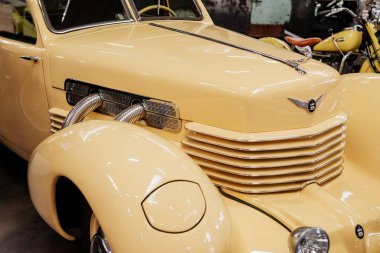 Sinsheim, Almanya - 16 Ekim 2018: Technik Müzesi. Arka planda motosikletli, krem renkli, eski model bir aracın sağ ve ön kısmı..