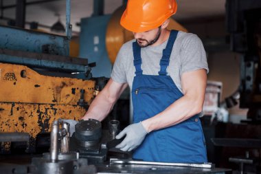 Büyük bir atık geri dönüşüm fabrikasında kasketli genç bir işçinin portresi. Mühendis, makinelerin ve diğer ekipmanların çalışmalarını izler..
