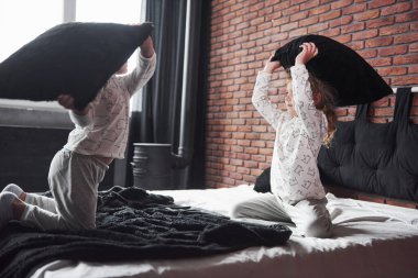 Yaramaz çocuklar, küçük oğlan ve kız yatak odasındaki yatakta yastık savaşı düzenlediler. Bu tür oyunları severler..