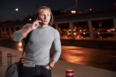 Gergin görünüyorsun. Genç, şık bir adam, gece caddesinde yol kenarında yürüyor ve telefonda konuşuyor..