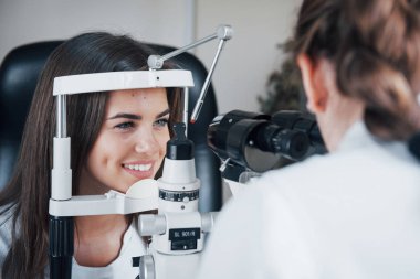 İyi sonuçlara benziyor. Optometrist genç ve güzel bir kadının görüşünü kontrol ediyor..