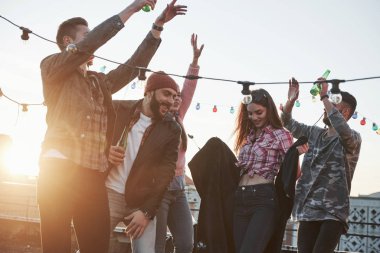 Eğleniyorum. Arka planda güzel güneş ışığı olan çatıda dans partisi. Genç şık insanlar..