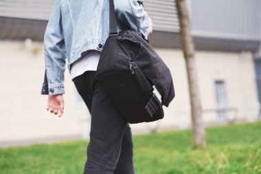 Omzunda çantasıyla havaalanına koşan yakışıklı bir genç..