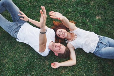 Parktaki çimlerin üzerinde yatan romantik bir çift genç. Üst görünüm.