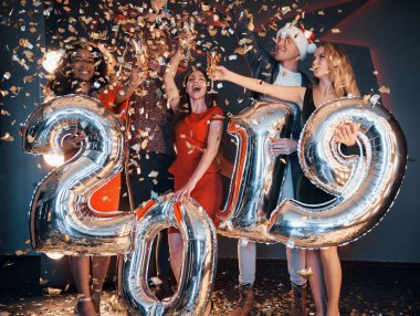 Güzel genç arkadaşlar, yeni yıl arifesinde eğleniyorlar, 2019 'un rakamlarını tutuyorlar.