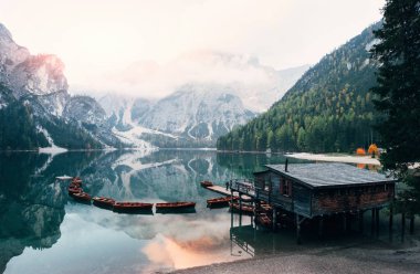 Güneşin doğuşu sudaki yansıması ve tepenin tepesinde. Dağlarla güzel bir manzara. Ahşap bina ve armudu olan turistik bir yer..