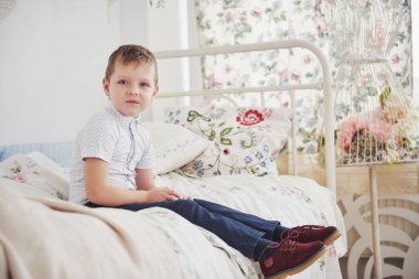 cute little boy sitting on bed 