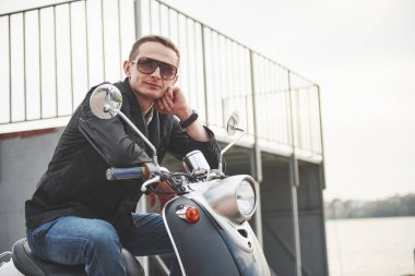 Güneş gözlüklü güzel çocuk mobiletiyle otururken kameraya bakıyor.