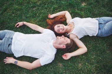 Parktaki çimlerin üzerinde yatan romantik iki genç insan. Mutlu görünüyorlar. Yukarıdan görüntüle