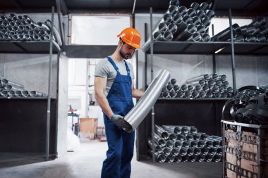 Büyük bir metal fabrikasında kasketli genç bir işçinin portresi. Shiftman bitmiş ürünlerin deposunda..