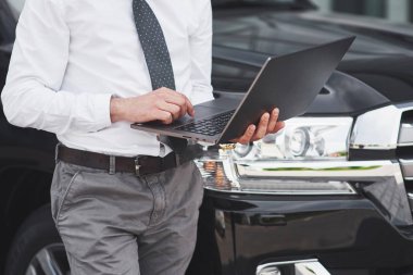 Adam bir dizüstü bilgisayarda çalışan ve mobil cihazlar üzerinde test yapan bir adam.