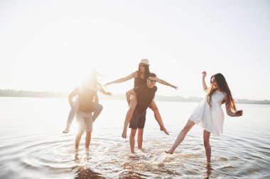 Mutlu arkadaşlar kumsalda eğlenir - Gençler yaz tatillerinde açık havada oynarlar.