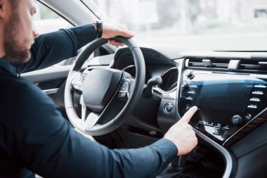 Kendine güvenen genç işadamının yeni arabasının direksiyonunda oturması..