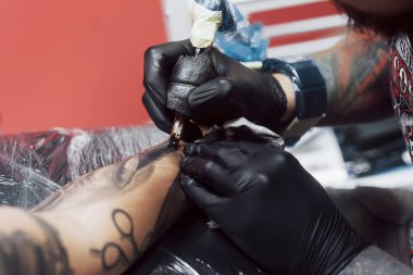 Dövme makinesini kapat. Siyah steril eldivenler ustası. Kuaförde resim yapıyor..