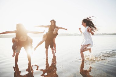 Mutlu arkadaşlar kumsalda eğlenir - Gençler yaz tatillerinde açık havada oynarlar.