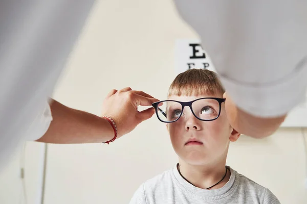 仕様を見ている男の子 医者は子供に新しい黒眼鏡を与える彼のビジョンのために — ストック写真