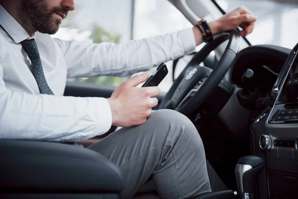 Zadowolony Młody Biznesmen Patrząc Telefon Komórkowy Podczas Jazdy Samochodem — Zdjęcie stockowe