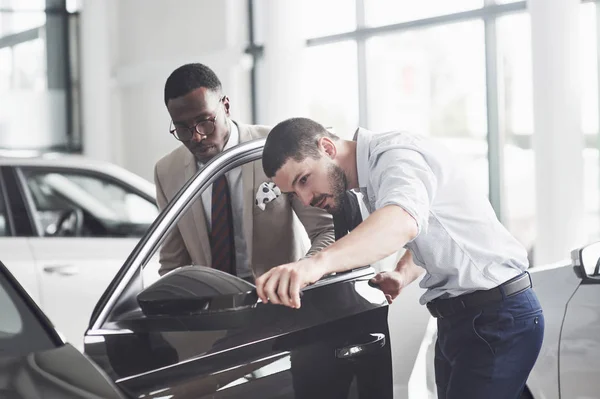 一个非洲男人买了一辆新车 检查了一辆正在和一个专业卖家交谈的汽车 — 图库照片