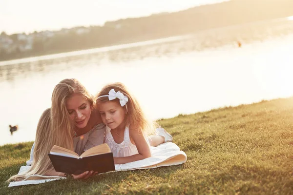 Çocuklu Bir Anne Çimenlerde Kitap Okur — Stok fotoğraf