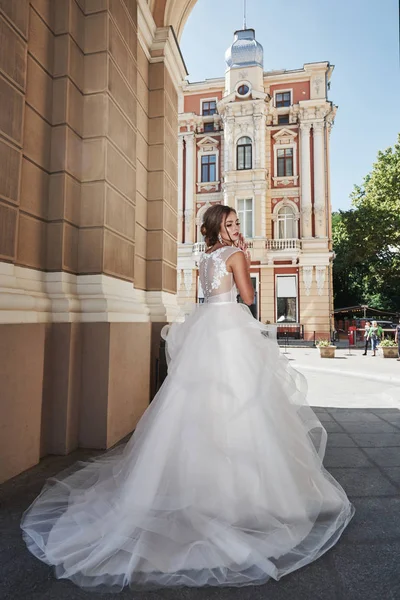 美しい 完璧なウェディングドレスを持つエレガントな花嫁は 美しい建築物の周りにポーズ — ストック写真