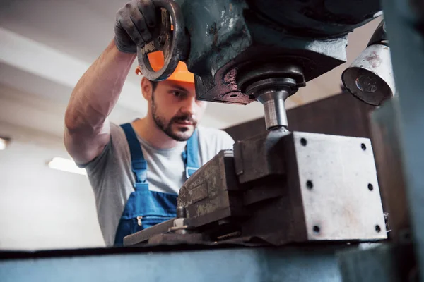 Portrait of a young worker in a hard hat at a large waste recycling factory. The engineer monitors the work of machines and other equipment.