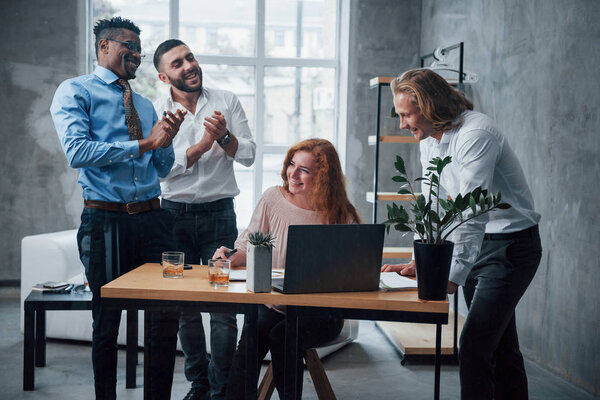 Happy workers. Young business team working on a project with laptop on table and smiling.