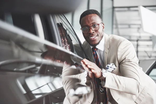 Bonito Homem Negro Concessionária Está Abraçando Seu Carro Novo Sorrindo — Fotografia de Stock