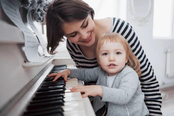 母親と娘が白いピアノを弾いている — ストック写真