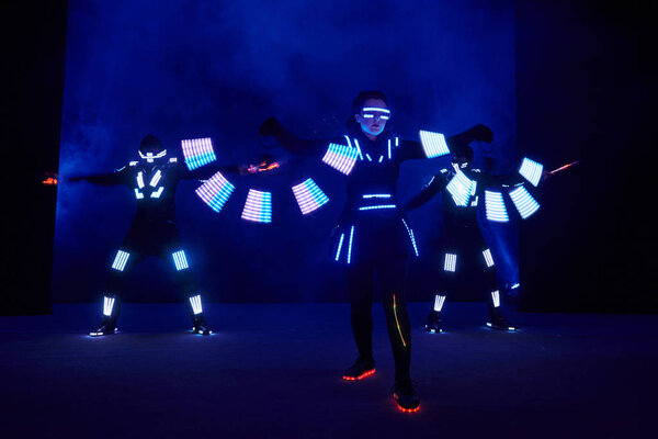 Laser show performance, dancers in led suits with LED lamp, very beautiful night club performance, party.