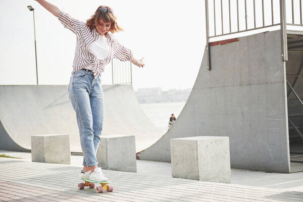 A young sports woman who rides in a park on a skateboard