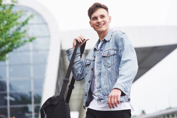 Young handsome man with a bag on his shoulder in a hurry to the airport.